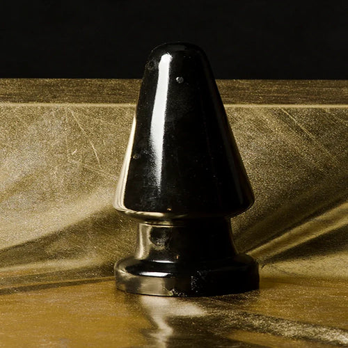 King Sized Anal Shocker schwarzer XXL-Analplug von Chambers of Love auf goldenem Hintergrund - große, glatte PVC-Oberfläche mit beeindruckenden Abmessungen für maximale Fülle